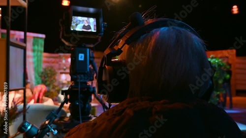 Cameraman filming a television talk show on a professional camera. Video production backstage in a dark studio photo