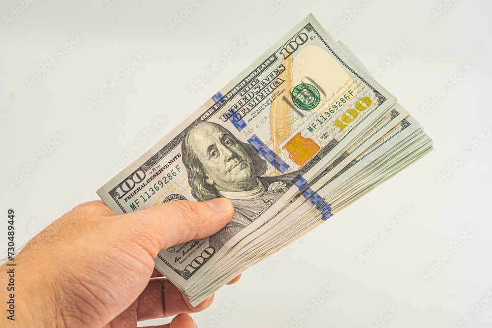 Hand holding money isolated on white background. One hundred Dollars bill on man hand to paying and giving. Hand holding money isolated on white background. One hundred Dollars bill on man hand to paying and giving.