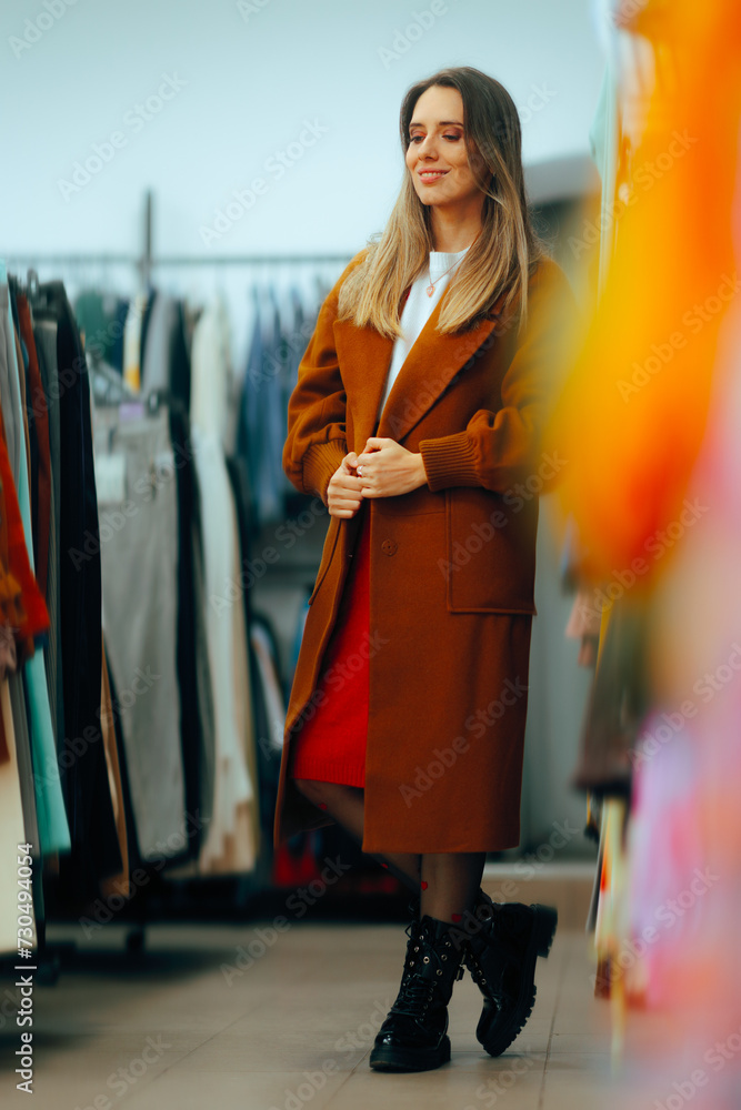 Girl Wearing a Long Brown Overcoat in a Fashion Store. Fashion girl visiting a clothing store in sale season
