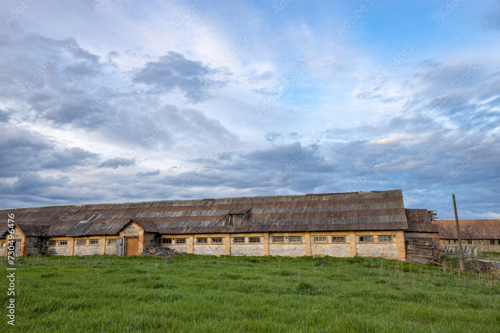 An old farm building against the background of the sky and green grass.