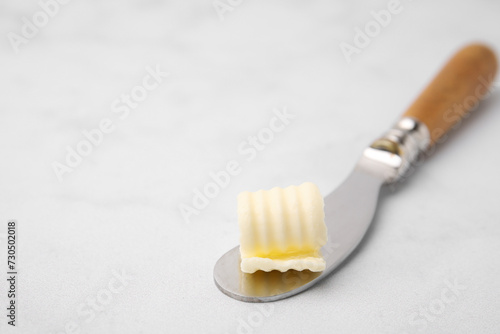 Tasty butter curl and knife on white table  closeup. Space for text