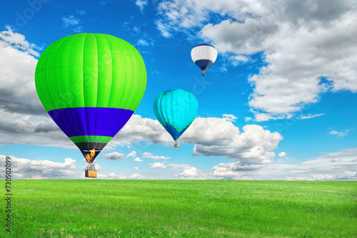 Bright hot air balloons flying over green field