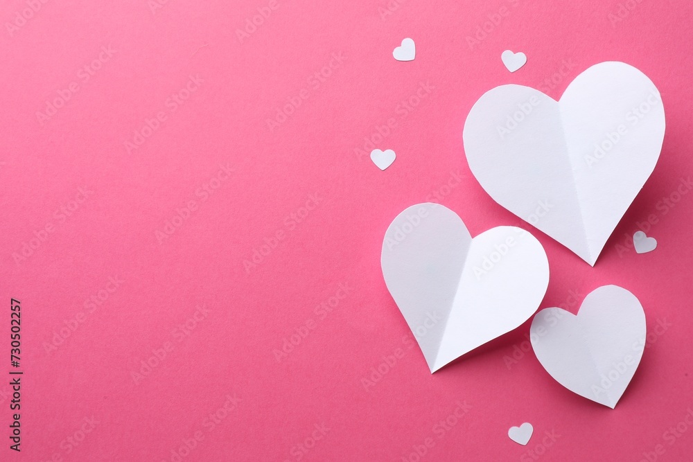 White paper hearts on pink background, flat lay. Space for text