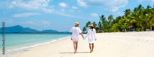 Koh Mook a young couple of caucasian men and Thai Asian woman walking at the beach in Thailand © Fokke Baarssen