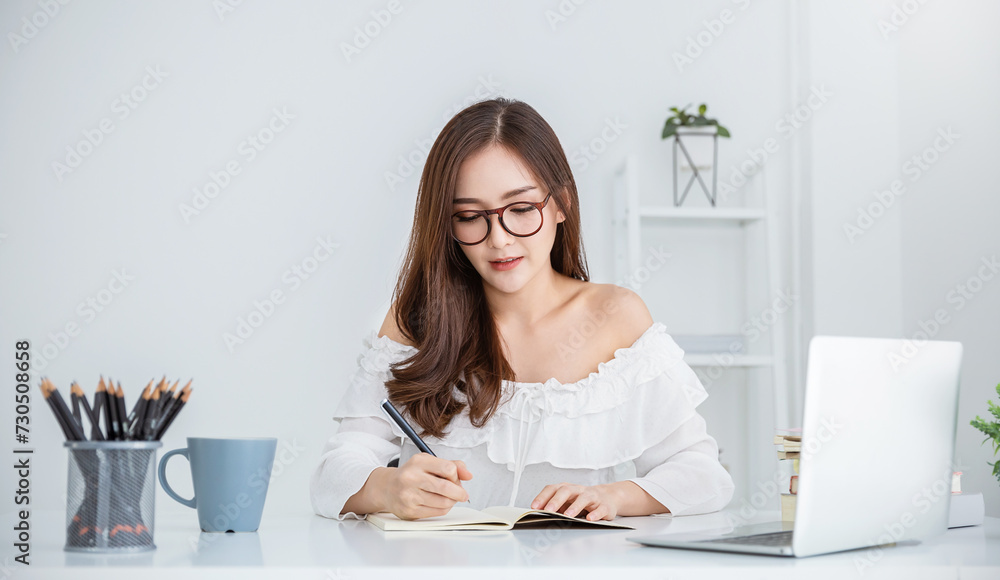 Portrait young asian business woman write notebook laptop in home office. Beautiful asian girl at desk computer take home order. Startup business asia woman online sme, assistant or secretary.