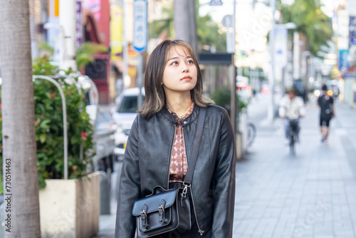 沖縄県那覇市の国際通り周辺を寒い冬に歩く若い２０代の沖縄県出身女性 A young woman from Okinawa Prefecture in her 20s walking around Kokusai-dori Street in Naha City, Okinawa Prefecture in a cold winter photo