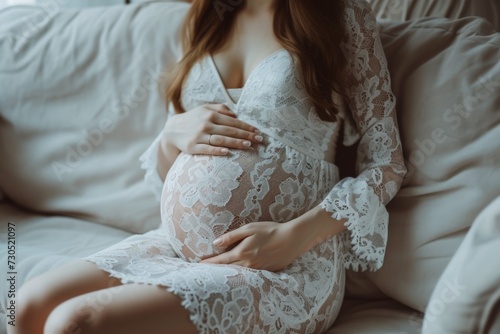 Pregnant woman in lace dress resting on couch