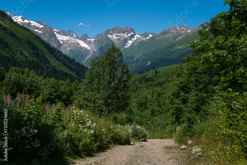 View of the Dombay-Ulgen gorge in the mountains of the North Caucasus and the trail to the Chuchkhur waterfall near the village of Dombay on a sunny summer day, Karachay-Cherkessia, Russia © Ula Ulachka