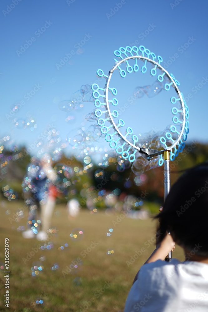 Naklejka premium 風車泡機で遊ぶ少年 / Boy playing with windmill foam machine