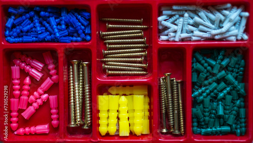 Organizador rojo de taquetes y tornillos de diferentes tamaños y colores