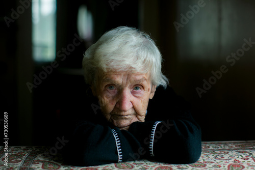 A poignant close-up portrait of a gray-haired old woman.