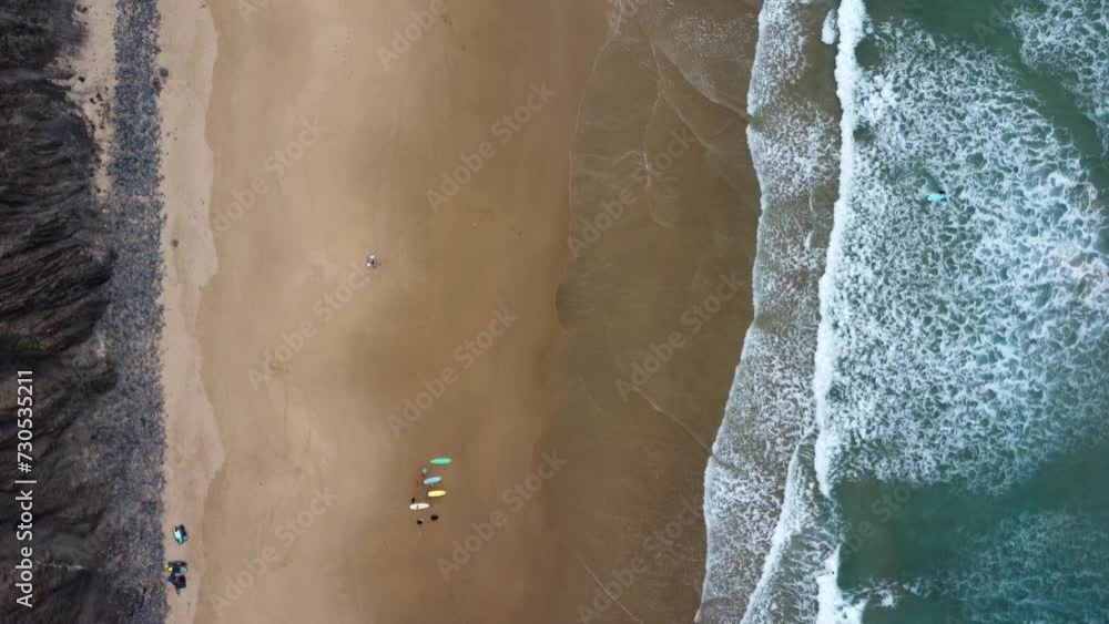 Drone shot of the coast with surfers in Arrifana beach, Portugal. People are resting on the beach between a session of surfing. The might be remotely working and enjoying their break. Drone shot of the coast with surfers in Arrifana beach, Portugal. People are resting on the beach between a session of surfing. The might be remotely working and enjoying their break.