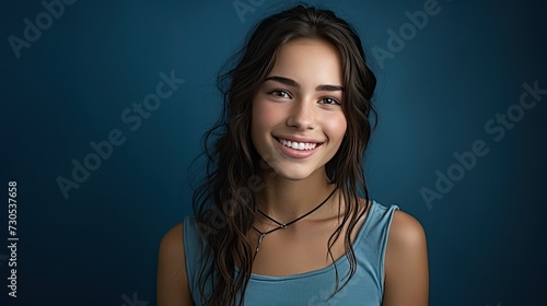 A smiling girl with thick dark hair on a blue background.