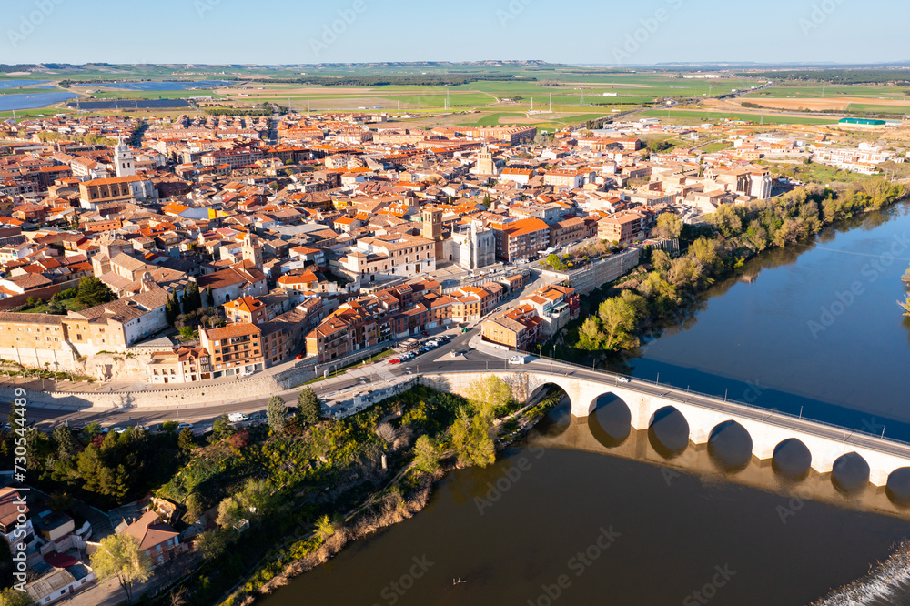 Scenic drone view of small ancient Spanish town of Tordesillas on banks of Duero river in province of Valladolid on sunny spring day.. - obrazy, fototapety, plakaty 