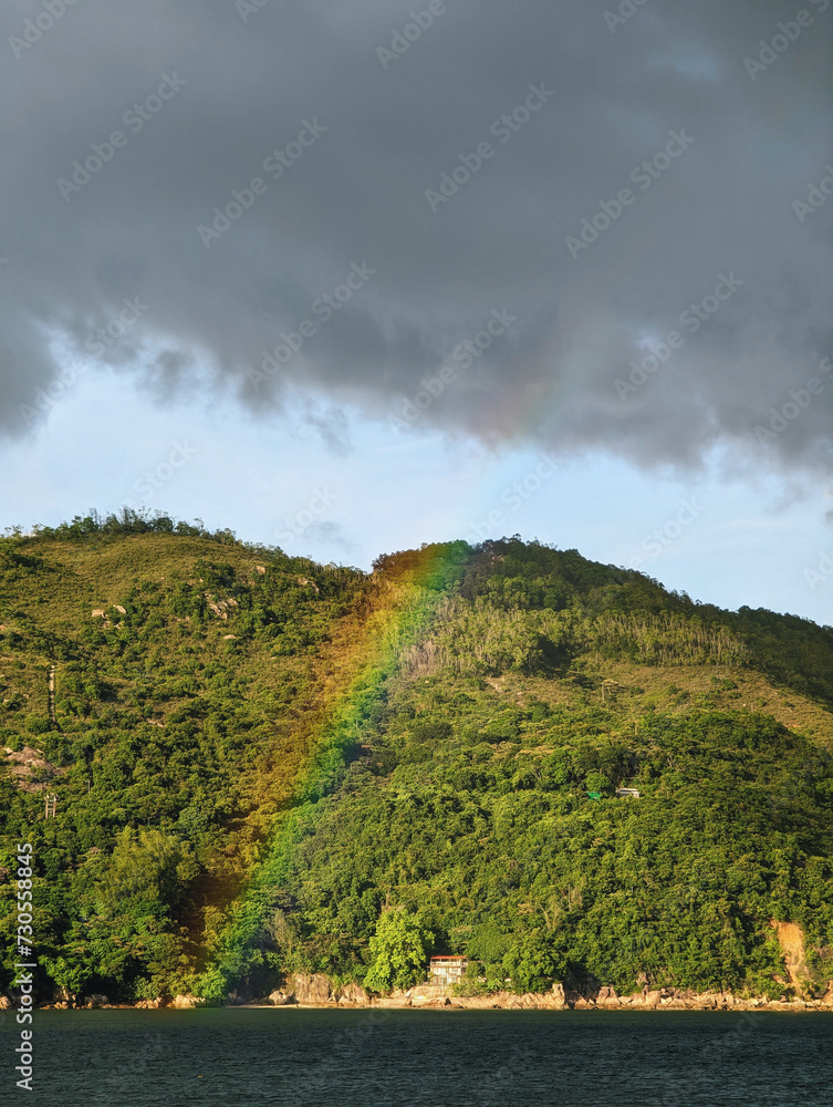 Fototapeta premium A beautiful natural scene where a vibrant rainbow is visible against a mountain.