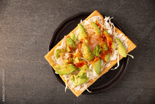 Fried wheat flour toast with pickled pork skin, sour cream and vegetables with hot sauce, in Mexico is called Chicharron preparado, traditional street food, pickled pork skin are known as Cueritos.