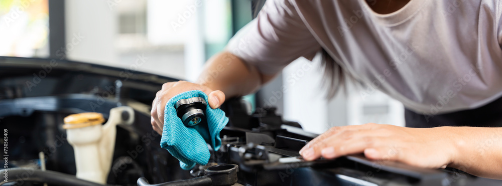 This woman may be checking the coolant level or looking for a leak. Panorama concept. This woman may be checking the coolant level or looking for a leak. Panorama concept.