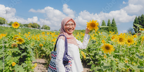 muslim woman smile in a field of sunflowers on summer in japan photo