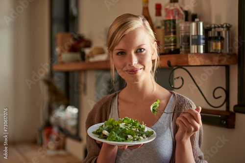 Portrait, woman and eating salad in kitchen at home, nutrition and fresh leafy greens for healthy diet. Vegetables, bowl and face of hungry person with food, fork and organic vegan meal for wellness