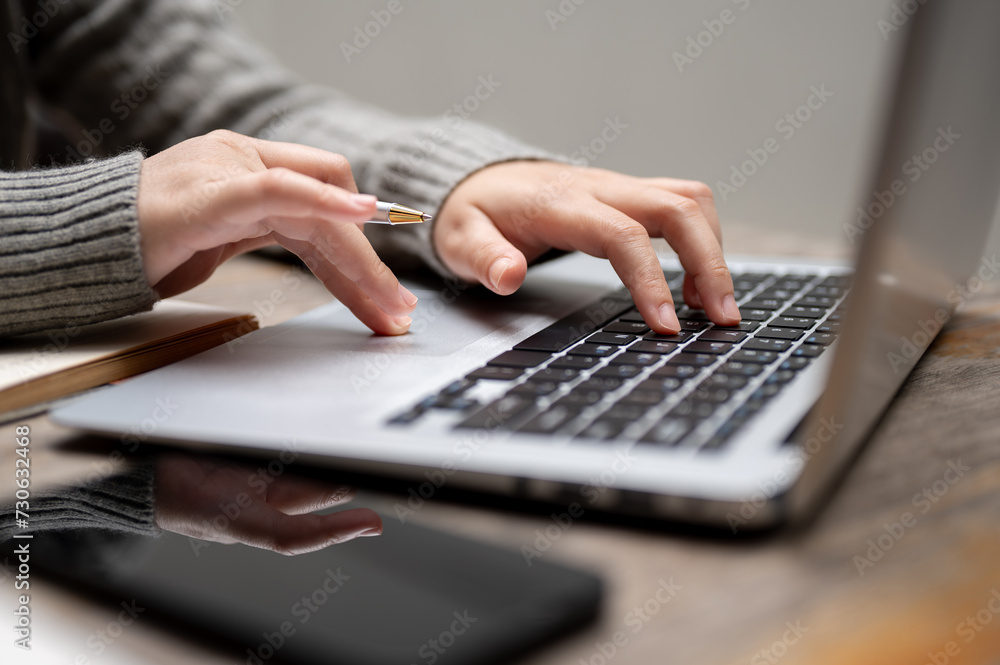 Close-up image of a woman typing on a keyboard, working on her laptop computer at a table. Close-up image of a woman typing on a keyboard, working on her laptop computer at a table.