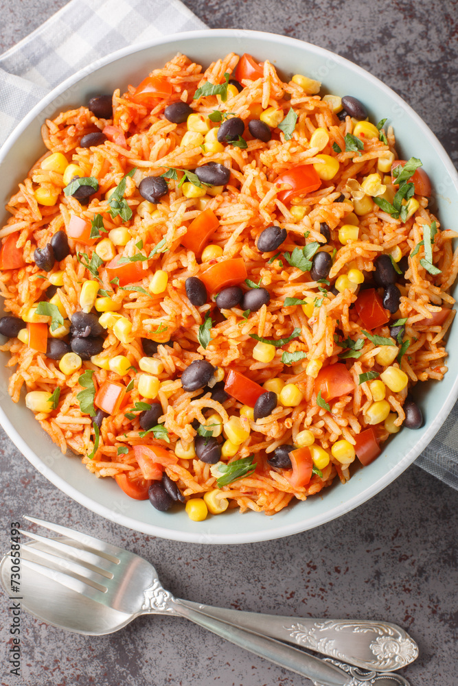 Mexican tomato rice with black beans, onions and corn close-up in a bowl on the table. Vertical top view from above Mexican tomato rice with black beans, onions and corn close-up in a bowl on the table. Vertical top view from above