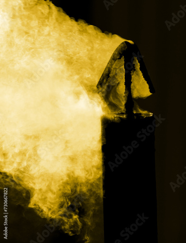Yellow smoke from a chimney isolated black background