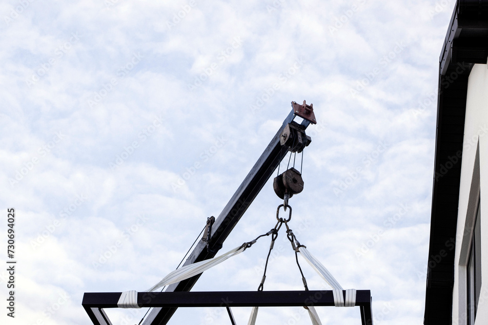 The crane lifts the metal structure. The cargo is lifted into the air by a crane. Construction. Construction site The crane lifts the metal structure. The cargo is lifted into the air by a crane. Construction. Construction site