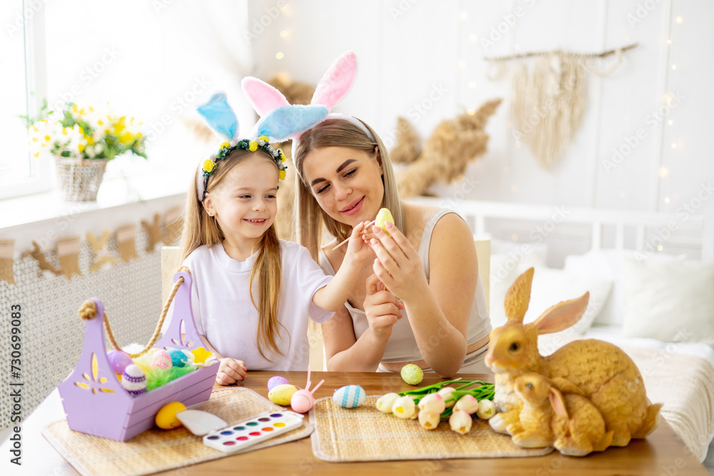 easter, a mother with a little daughter with hare ears on her head are preparing for the holiday by coloring colorful eggs, lifestyle, preparing a happy family with a child for Easter easter, a mother with a little daughter with hare ears on her head are preparing for the holiday by coloring colorful eggs, lifestyle, preparing a happy family with a child for Easter