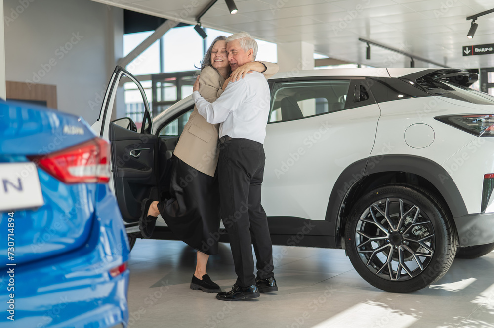Mature Caucasian couple hugging with happiness while buying a new car. Mature Caucasian couple hugging with happiness while buying a new car.