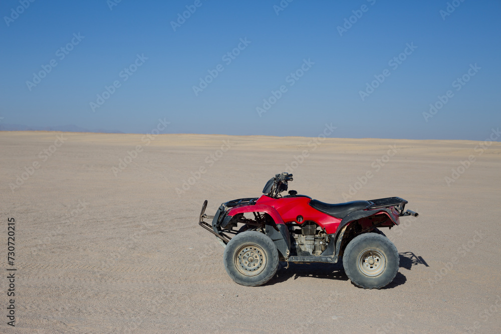 ATV for an extreme excursion against the backdrop of the desert and clear sky. Side view of Arabian desert skyline and quad bike ATV for an extreme excursion against the backdrop of the desert and clear sky. Side view of Arabian desert skyline and quad bike