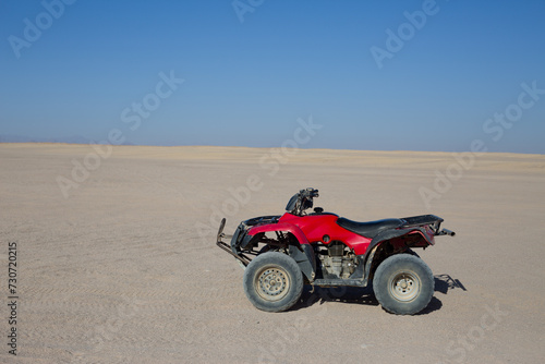 ATV for an extreme excursion against the backdrop of the desert and clear sky. Side view of Arabian desert skyline and quad bike