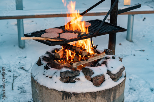 Hamburger on cooking grate over big flames photo