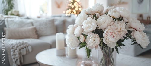 In the living room of a house, there is a vase with white flowers placed on a table, adding beauty to the furniture arrangement.