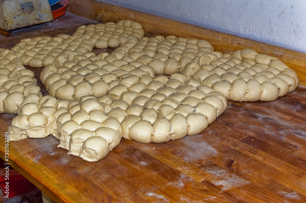 Fresh bread dough resting at wooden table in bakery.