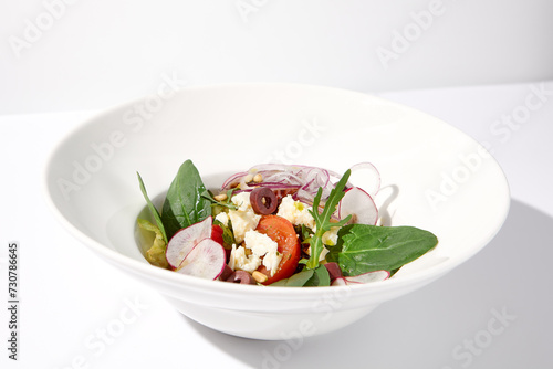Greek salad isolated on a white background with crisp vegetables and feta cheese