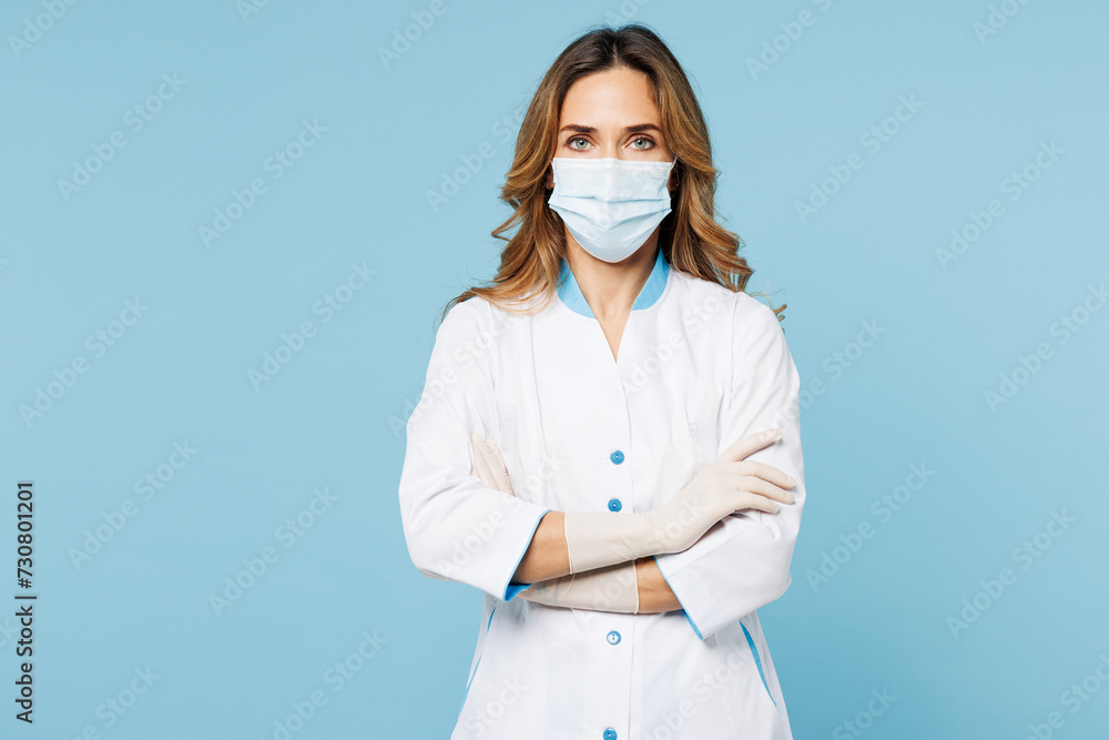 Female doctor woman wear white medical gown suit protective sterile mask work in hospital clinic office hold hands crossed folded isolated on plain blue background studio Health care medicine concept Female doctor woman wear white medical gown suit protective sterile mask work in hospital clinic office hold hands crossed folded isolated on plain blue background studio Health care medicine concept