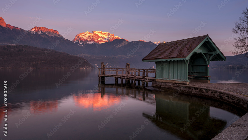 Fototapeta premium Paysage du lac d'Annecy en Haute-Savoie au coucher du soleil en hiver entouré de montagne dans les Alpes françaises