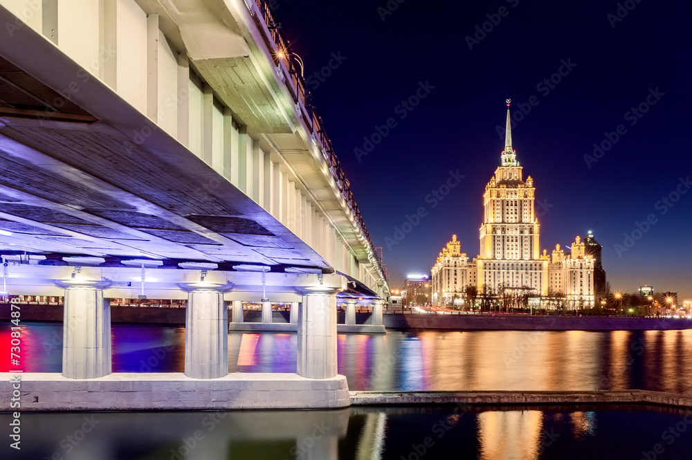Stalin's skyscraper on the banks of the Moscow River in the illumination of evening lighting against the background of the sunset sky. Panorama
