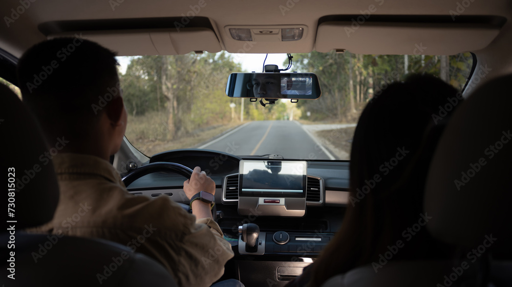 Rear view shot of young couple driving on country road. Traveling and vacation concept