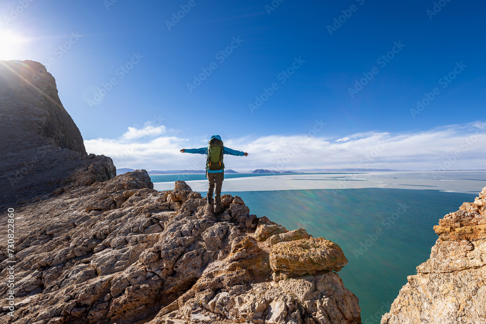 Woman hiker enjoy the view on mountain top cliff edge at lakeside