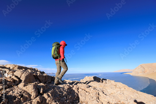 Woman hiker enjoy the view on mountain top cliff edge at lakeside