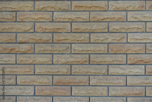 Background - beige brick veneer wall with grey mortar joints
