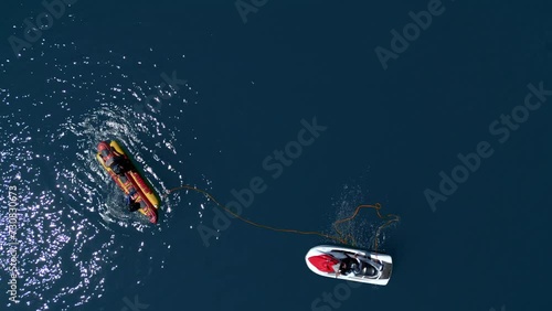 Young Hispanic Men Climbing Back onto Airhead Hot Dog in a Lake. Birds Eye View photo