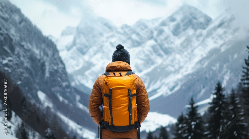 A man stands with her back and admires the view of snowy mountains. A traveler traveling on vacation in the most beautiful place in the world. Winter vacation