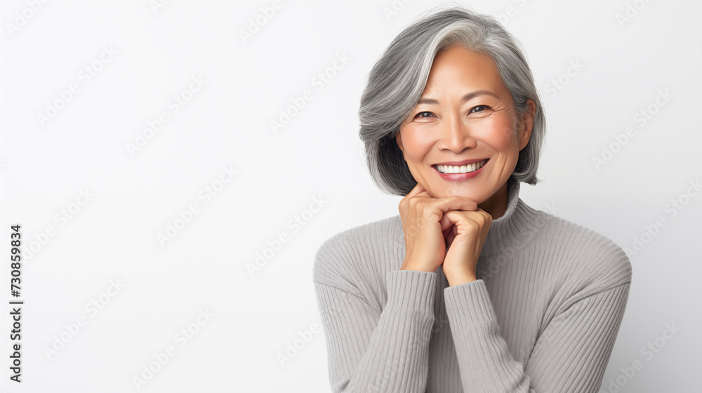 Woman in a sleek gray sweater, confidently resting her chin on her hands, with a bold smile and eyes reflecting determination, against a clean white background Woman in a sleek gray sweater, confidently resting her chin on her hands, with a bold smile and eyes reflecting determination, against a clean white background