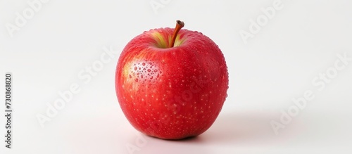 A red apple, a staple fruit and superfood, rests upon a white surface, showcasing a natural and local produce.