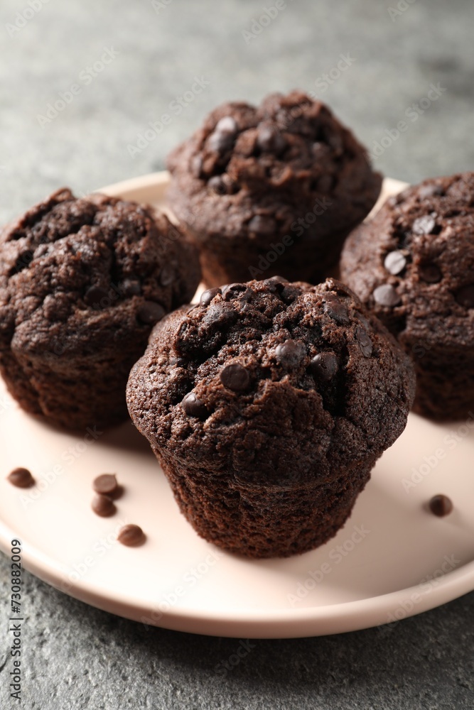 Delicious chocolate muffins on grey textured table, closeup Delicious chocolate muffins on grey textured table, closeup