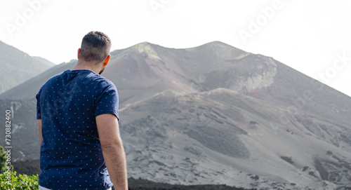 man from behind and standing, looking at the crater of a volcano