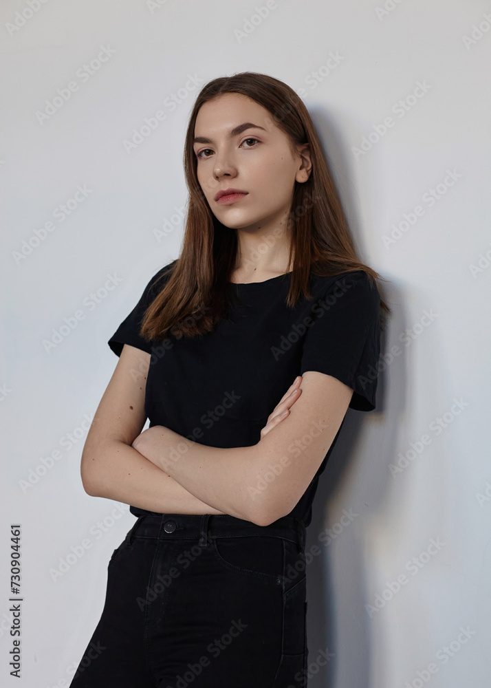 Fototapeta premium A sweet woman in a black T-shirt posing on a light background stood in a confident pose