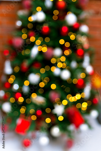 Abstract Blurry Christmas Tree Lights. A festive Christmas tree out of focus, creating a beautiful abstract pattern of colorful bokeh lights against a brick wall.